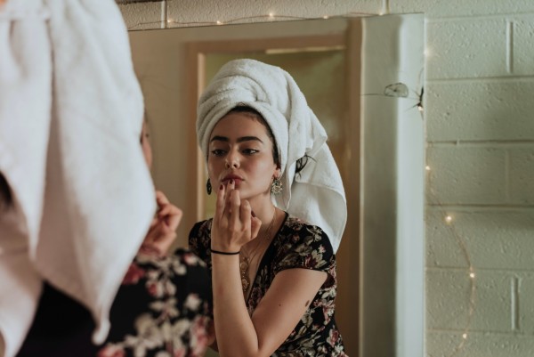 Woman In Front of The Mirror Putting A Skin Care Product On Her Lip 