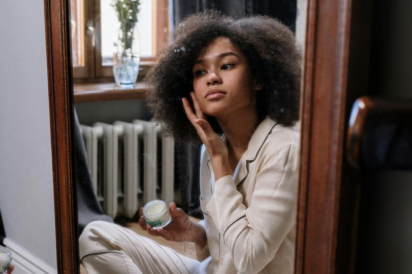 woman applying skincare product on face