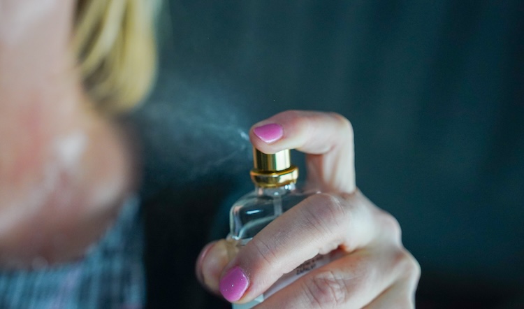 A white woman spraying perfume 