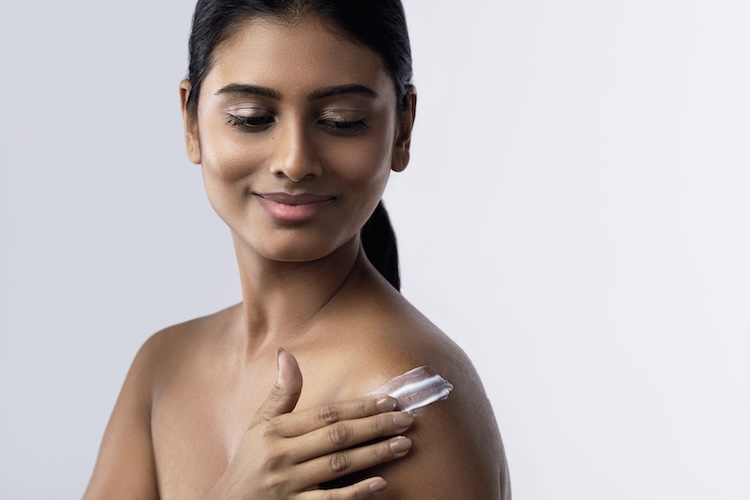 Indian woman applying body lotion 
