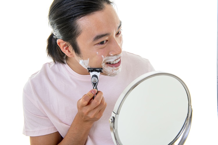 asian man with long hair shaving 