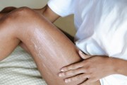Person with brown skin applying lotion to leg 