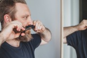 White Man using Mustache Comb to help cut his facial hair 